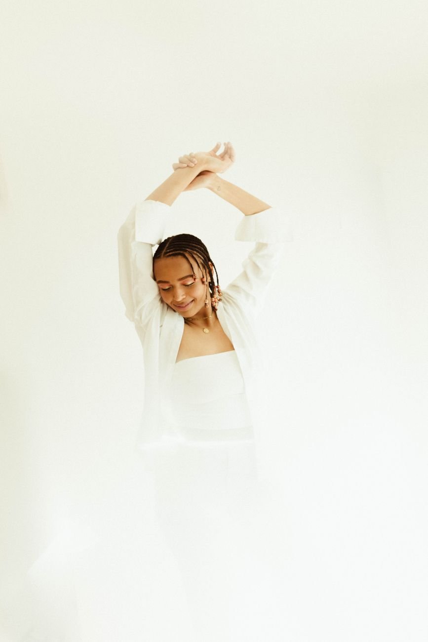 Elegant fashion portrait of a woman in a white outfit against a minimalist background