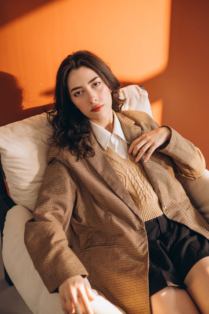 Woman in a stylish outfit poses in warm, elegant lighting indoors