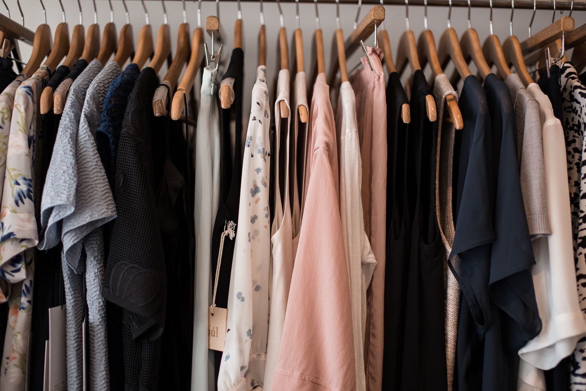 A stylish collection of women's clothing on wooden hangers in a boutique