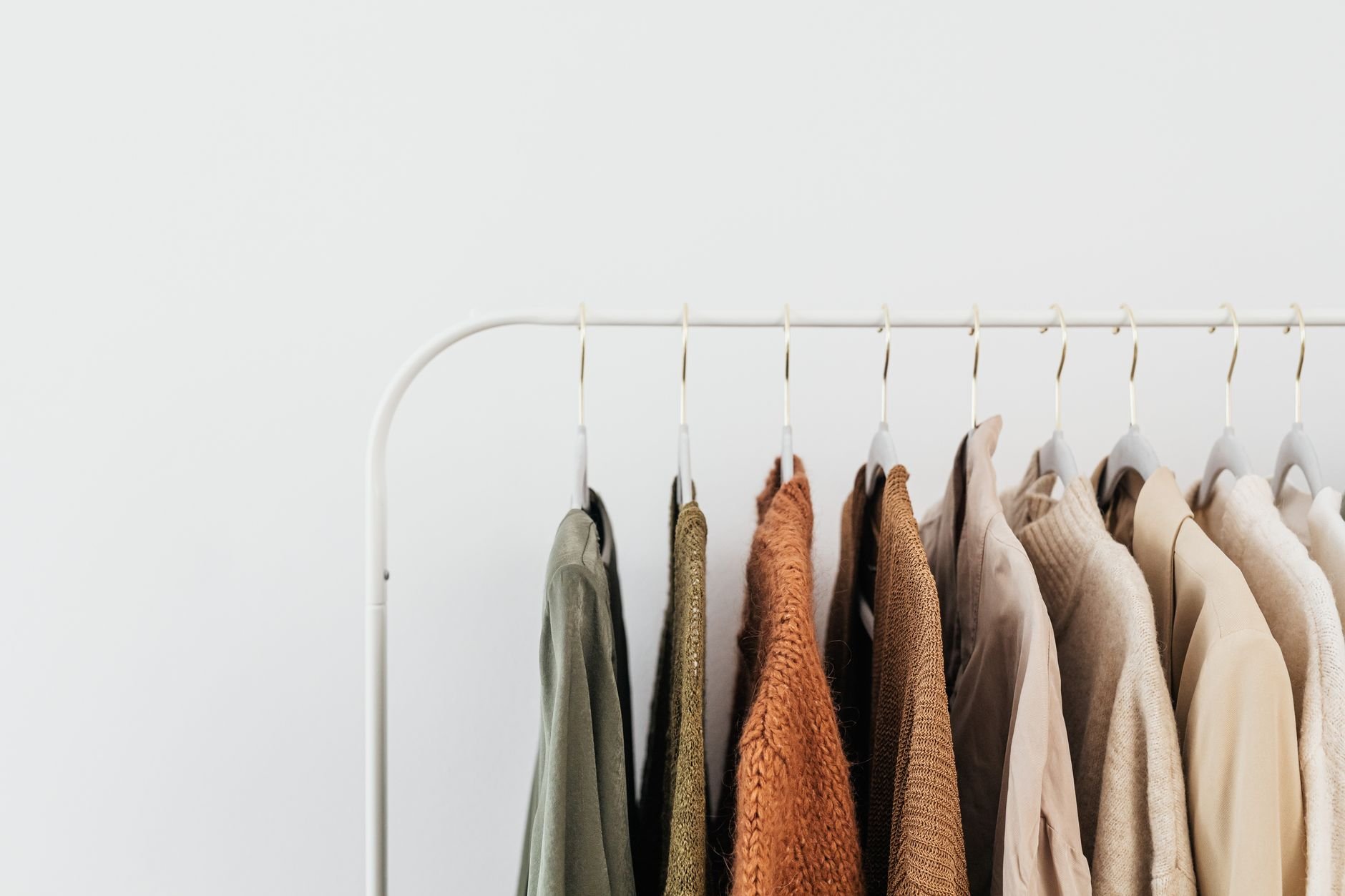 A minimalist clothing rack displaying neutral-toned outfits in an organized indoor setting